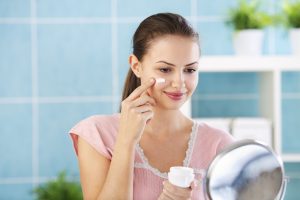 Woman putting cream on face